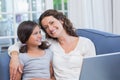 Happy mother and daughter sitting on the couch and using laptop Royalty Free Stock Photo