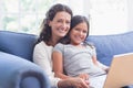 Happy mother and daughter sitting on the couch and using laptop Royalty Free Stock Photo