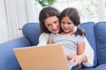 Happy mother and daughter sitting on the couch and using laptop Royalty Free Stock Photo