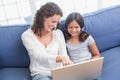 Happy mother and daughter sitting on the couch and using laptop Royalty Free Stock Photo