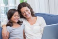 Happy mother and daughter sitting on the couch and using laptop Royalty Free Stock Photo