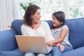 Happy mother and daughter sitting on the couch and using laptop Royalty Free Stock Photo