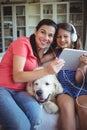 Happy mother and daughter sitting with pet dog and listening to music on headphones Royalty Free Stock Photo