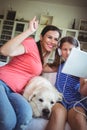 Happy mother and daughter sitting with pet dog and using digital Royalty Free Stock Photo