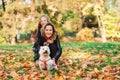 Happy mother and daughter walking with their dog in autumn park. Autumn time, weekend and holidays Royalty Free Stock Photo