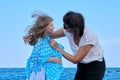 Happy mother and daughter walking together along sea beach, mom cares for her kid Royalty Free Stock Photo