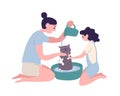 Happy mother and daughter washing cat at home. Funny mom and little girl taking care of domestic animal or pet. Daily