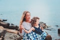 Happy mother and daughter wrapped in quilt blanket spending time together on the beach on summer vacation. Happy family traveling Royalty Free Stock Photo