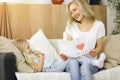Happy mother day in sunny flat. Child daughter congratulates mom and gives her postcard with heart drawing. Family