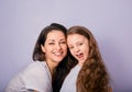 Happy mother and excited joying kid girl hugging with emotional smiling faces on purple background with empty copy space. Closeup Royalty Free Stock Photo