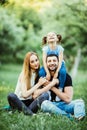 Happy mother, father and daughter in the park. Beauty nature scene with family outdoor lifestyle. Happy daughter on father back sm Royalty Free Stock Photo