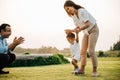 Portrait of a loving family spending quality time in nature, teaching their baby girl to walk