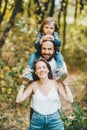 Happy mother, father and her cute son with long hair having fun rest in the autumn park. Vertical portrait Royalty Free Stock Photo