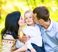 Happy mother and father kissing his little son in park Royalty Free Stock Photo