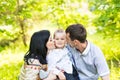 Happy mother and father kissing his little son in park Royalty Free Stock Photo