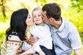 Happy mother and father kissing his little son in park Royalty Free Stock Photo