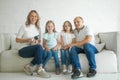 Happy mother and father with little children sitting on sofa and laughing while having fun together at home during weekend Royalty Free Stock Photo