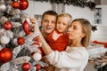 Happy mother, father and little son decorating christmas tree together at home, Little boy is crying and wants to take toy ball in Royalty Free Stock Photo