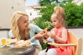 Happy mother feeding daughter with cake at cafe Royalty Free Stock Photo