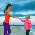 Happy mother giving child high five on seacoast in evening