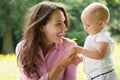 Happy mother giving flower to baby in the park