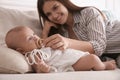 Happy mother giving pacifier to her cute little baby on sofa at home Royalty Free Stock Photo