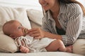 Happy mother giving pacifier to her cute little baby on sofa at home Royalty Free Stock Photo