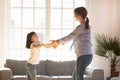 Happy mother having fun, dancing with adorable daughter at home