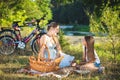 Happy young mother having picnic under tree near river with daughter Royalty Free Stock Photo