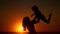 Happy mother and her adorable little girl having fun on the beach. Mom lifting little girl while enjoying family time by Royalty Free Stock Photo