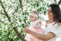 Happy mother and her baby daughter. Little girl in pink dress. Attractive beautiful female and cute infant