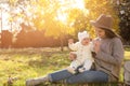 Happy mother with her baby daughter sitting on grass in autumn park, space for text Royalty Free Stock Photo