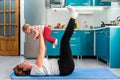 A happy mother with her baby is having fun doing fitness on the mat in the kitchen. Side view. The concept of home sports training Royalty Free Stock Photo