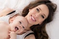 Happy mother and her baby son lying on a bed together. Happy family. Mother and newborn child. Royalty Free Stock Photo