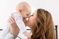 Happy mother and her baby son playing on a bed together. Happy family. Mother and newborn child. Royalty Free Stock Photo