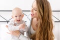 Happy mother and her baby son playing on a bed together. Happy family. Mother and newborn child. Royalty Free Stock Photo