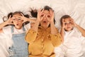 Happy mother and her children making glasses with their hands on bed, top view Royalty Free Stock Photo