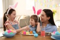 Happy mother with her children painting Easter eggs at table indoors Royalty Free Stock Photo