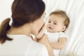 Happy, loving mother kissing her baby boy's little feet while cuddling on bed at home Royalty Free Stock Photo