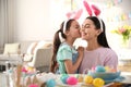 Happy mother with her cute daughter painting Easter eggs at table indoors Royalty Free Stock Photo