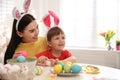 Happy mother with her cute son painting Easter eggs at table indoors Royalty Free Stock Photo