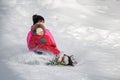 Happy mother and her daughter enjoying a sledge ride down the hils