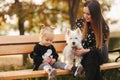 Happy mother and her daughter playing with dog in autumn park. Family, pet, domestic animal and lifestyle concept Royalty Free Stock Photo