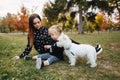 Happy mother and her daughter playing with dog in autumn park. Family, pet, domestic animal and lifestyle concept Royalty Free Stock Photo