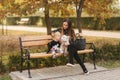 Happy mother and her daughter playing with dog in autumn park. Family, pet, domestic animal and lifestyle concept Royalty Free Stock Photo