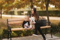 Happy mother and her daughter playing with dog in autumn park. Family, pet, domestic animal and lifestyle concept Royalty Free Stock Photo