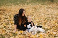 Happy mother and her daughter playing with dog in autumn park. Family, pet, domestic animal and lifestyle concept Royalty Free Stock Photo