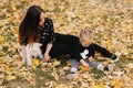 Happy mother and her daughter playing with dog in autumn park. Family, pet, domestic animal and lifestyle concept Royalty Free Stock Photo