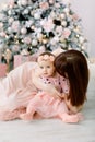 Happy mother with her daughter playing near the Christmas tree. Mother kissing and hugging her daughter. Christmas Royalty Free Stock Photo