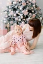 Happy mother with her daughter playing near the Christmas tree. Mother kissing and hugging her daughter. Christmas Royalty Free Stock Photo